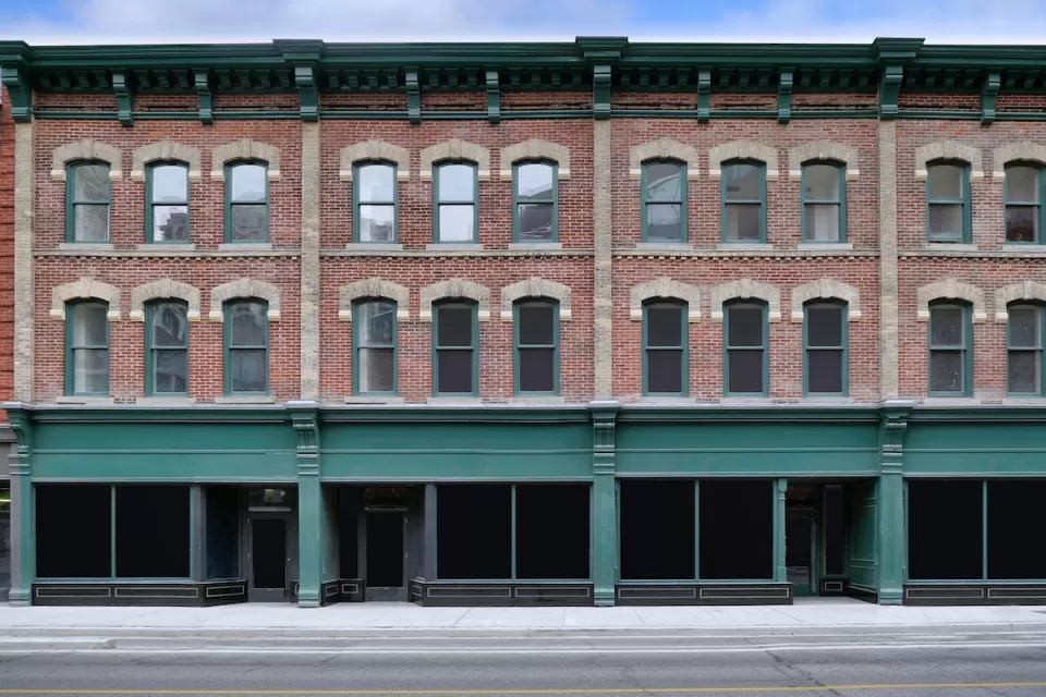 Brick building with storefronts on ground floor and apartments on two floors above.